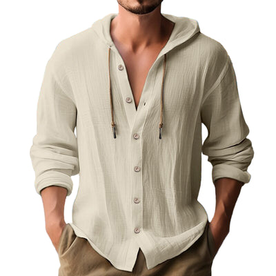 Man wearing a beige hoodie with a beach in the background